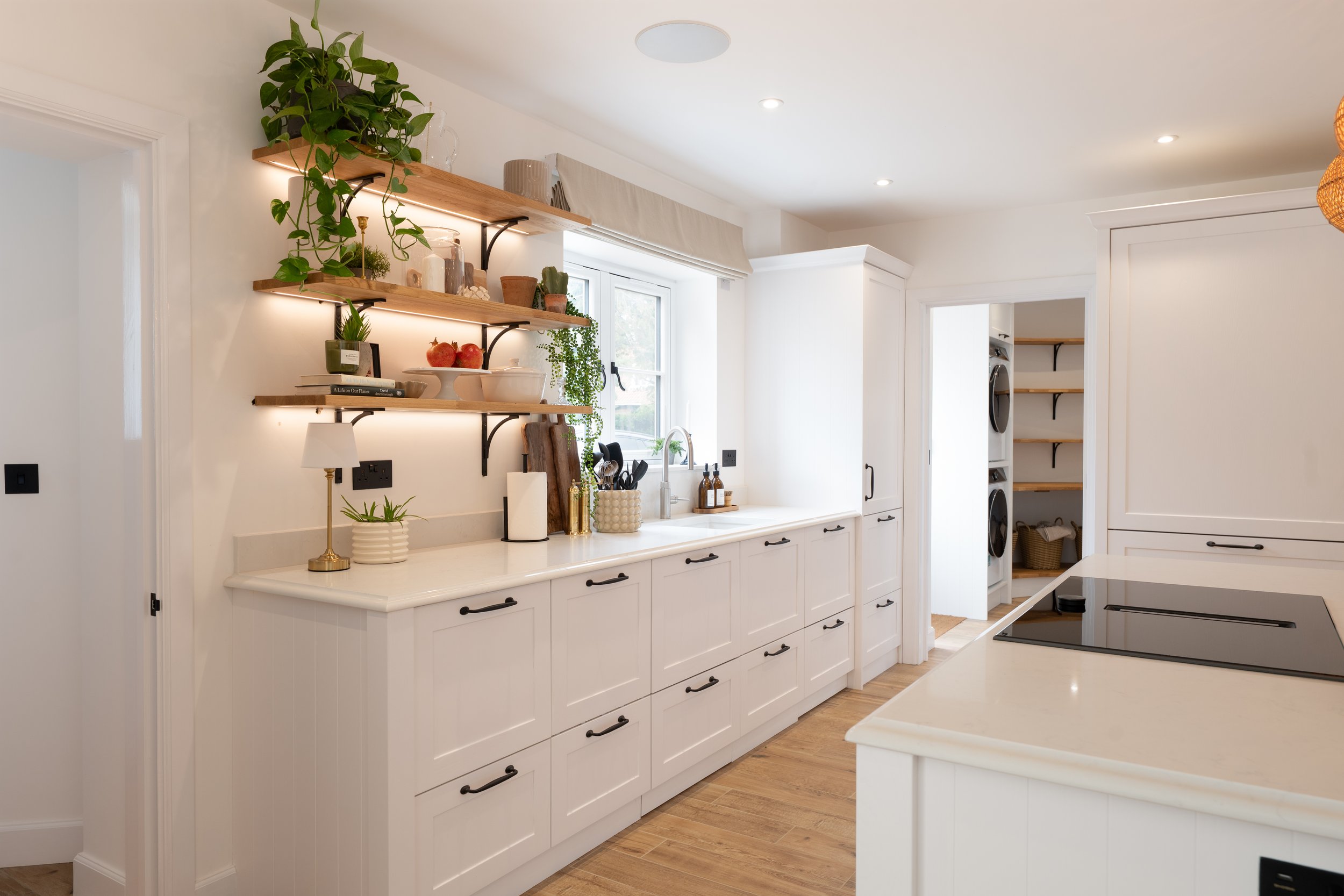 Painted Shaker kitchen with illuminated oak shelving, quartz worktops and utility room beyond