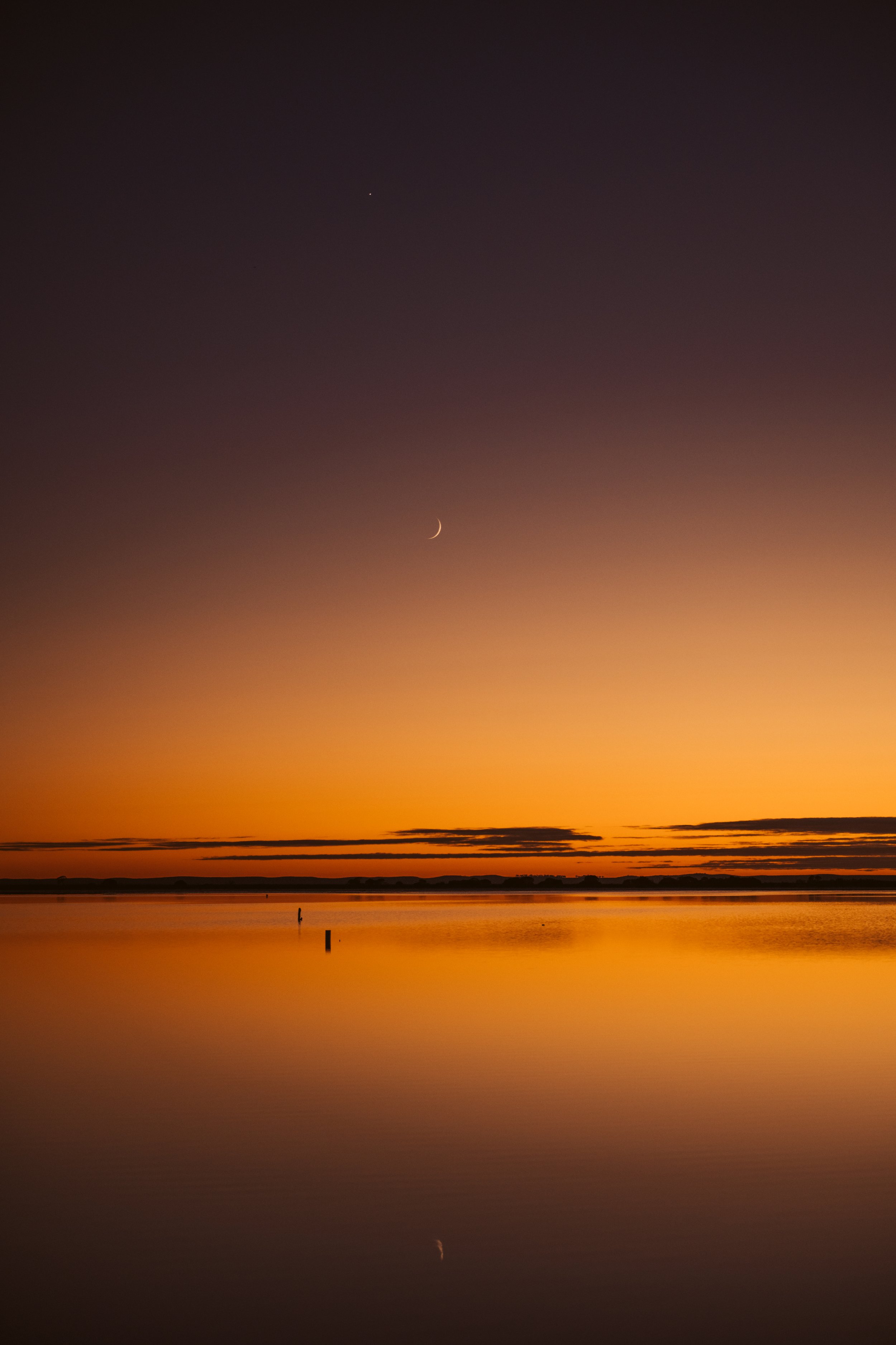  Thin crescent moon above Lake Tyrrell at sunset, with golden light reflecting across the still salt lake in Victoria. 