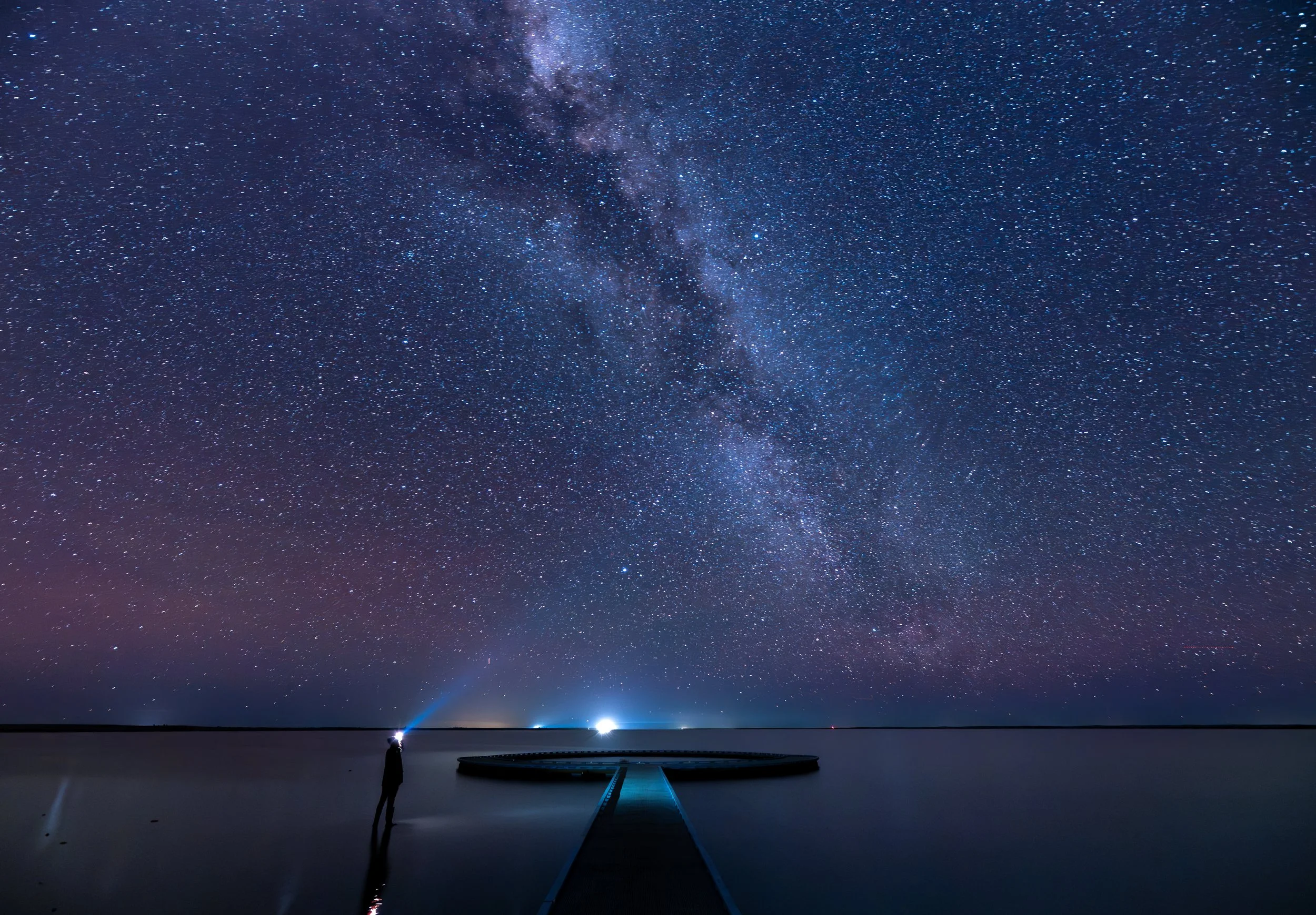 Milky Way stretching across the night sky above Lake Tyrrell, with a person standing beside the circular viewing platform under a star-filled sky in Victoria.