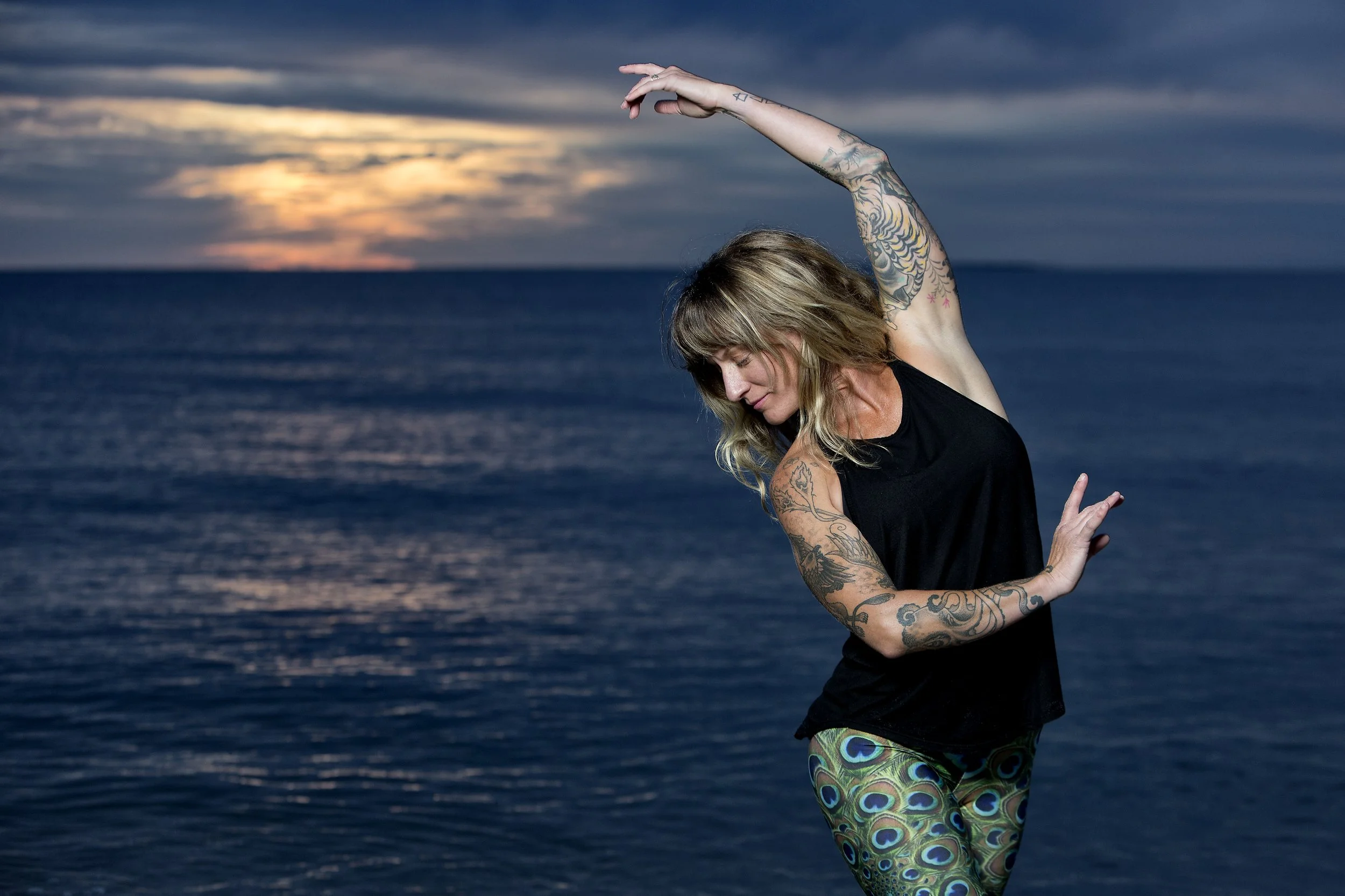 Instructor Caitlin Marcoux practicing yoga at sunset. A talented teacher in Amesbury known for her deep knowledge of anatomy, strength-based flow, and mindful movement. Tattoos always welcomed. 