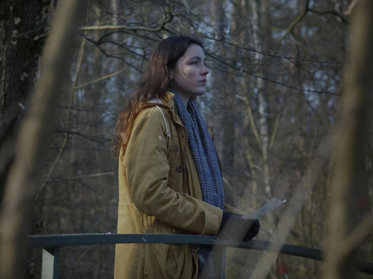 Still from A Letter to Home (2026), cinematography by Dorothea Pilz: a woman in a yellow coat and scarf in a wintry Berlin park