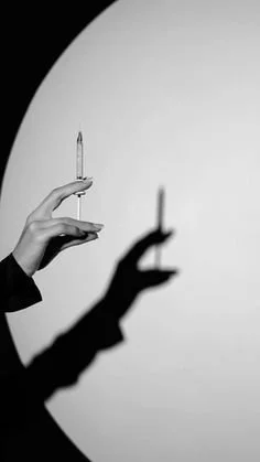 A hand holding a syringe with a shadow cast on a wall