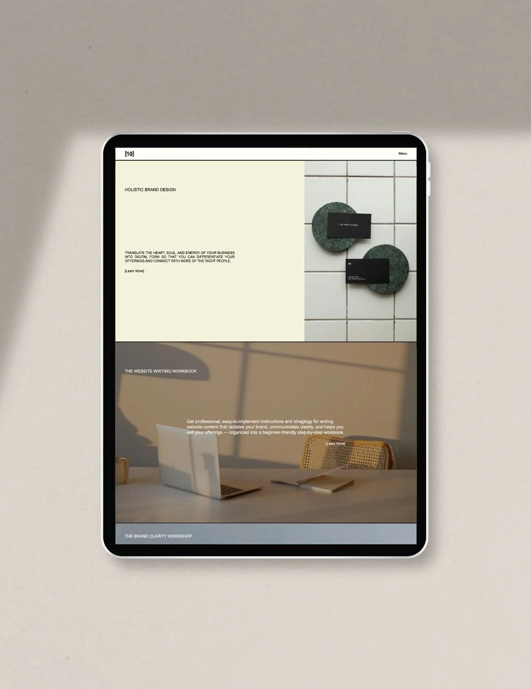 An iPad displaying a modern minimalist editorial style website home page with a split screen section with photo on half and pale yellow background with text on the other half and a full photo background with white text overlay section below.