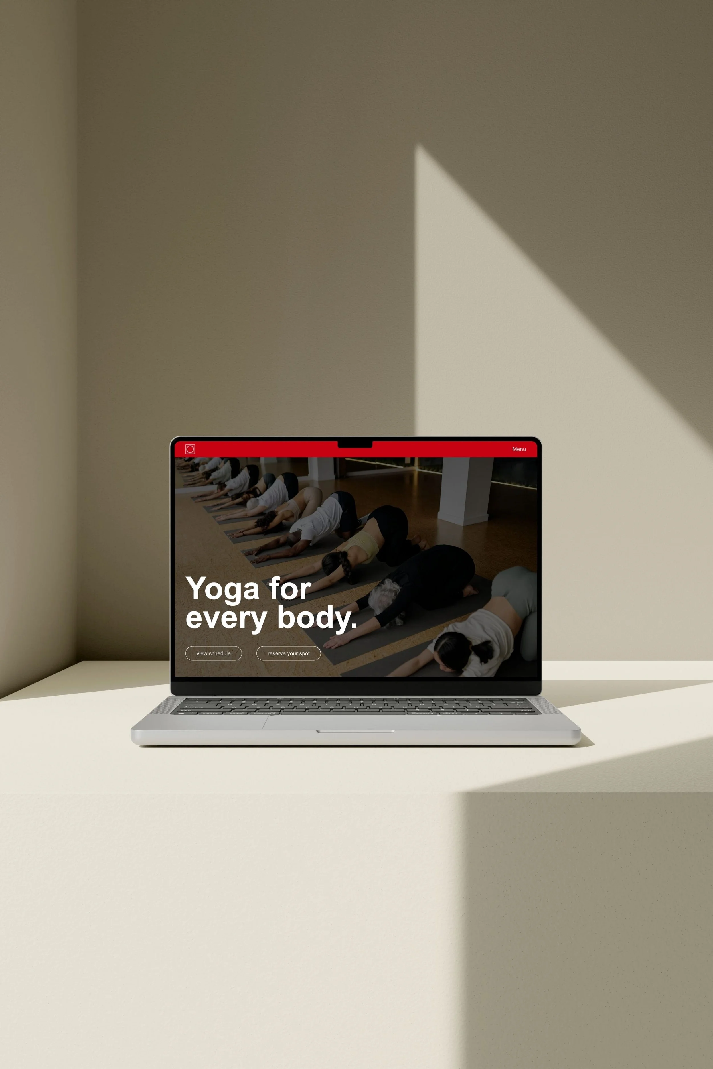 Laptop on a white surface displaying the Peterborough Yoga website.