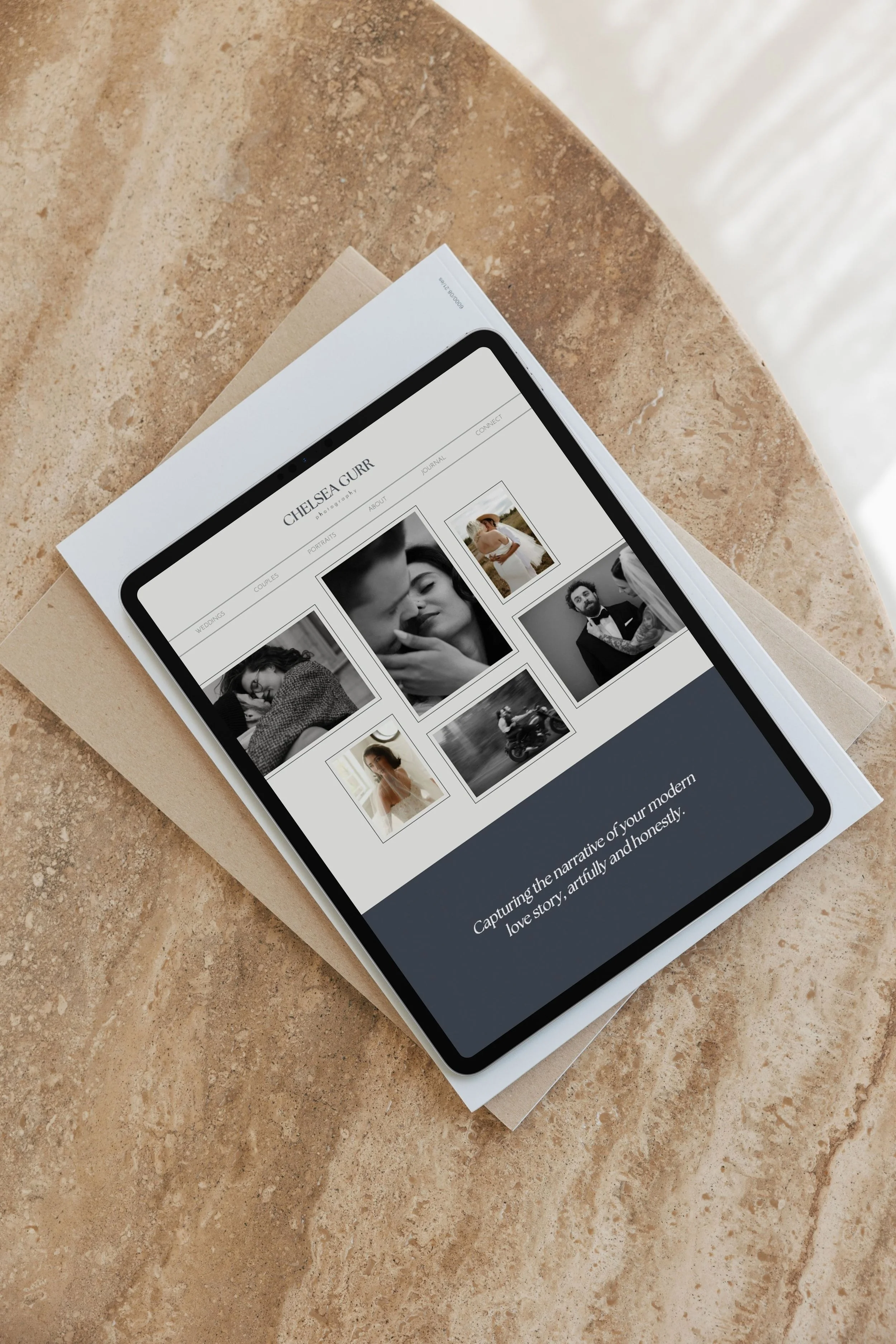 A tablet displaying a photographers website with a collage of photos on a soft white background and dark blue background section below.