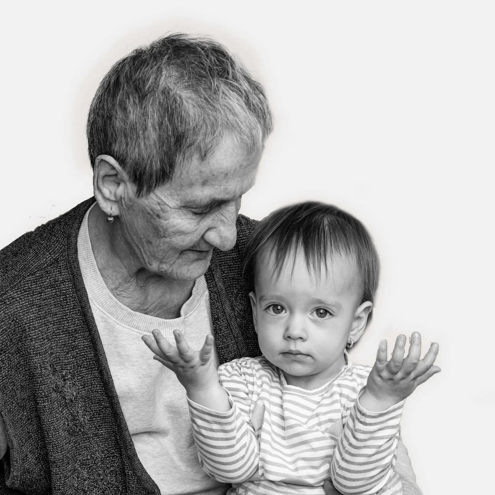 A black-and-white photo of an elderly woman with short gray hair and a young girl with straight hair and earrings, both making playful gestures with their hands.