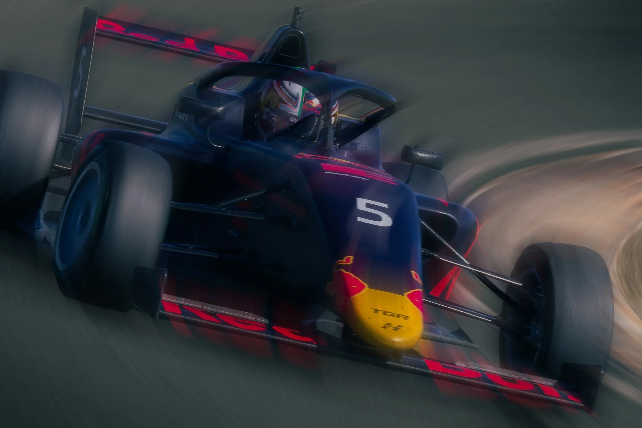 A Formula 1 race car with the number 5 and Red Bull branding on a race track during a high-speed turn.