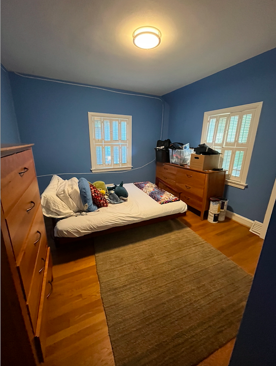 A cluttered bedroom in need of organization, decluttering and a new floor plan.