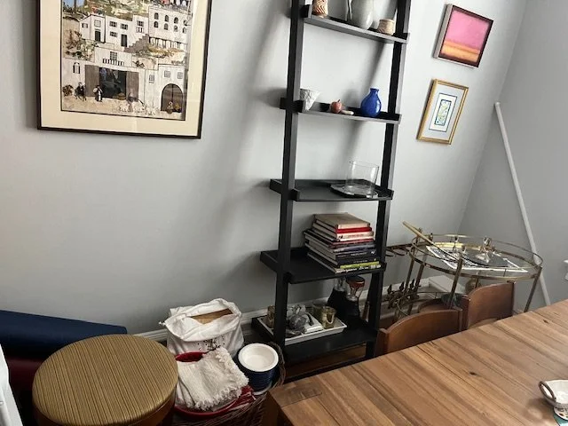 Dining room corner with shelving unit, books, and art