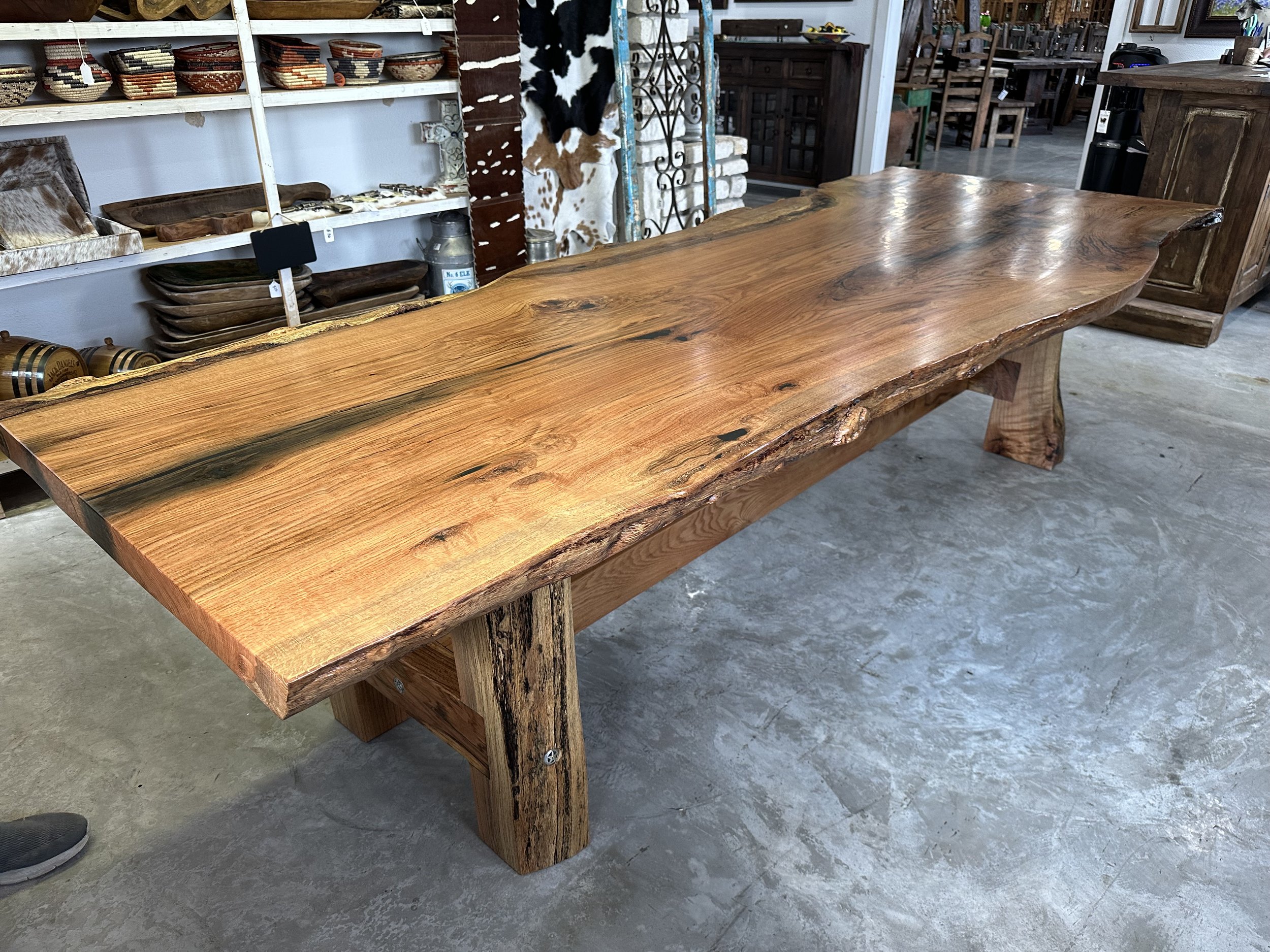 A large, rustic wooden dining table with a natural edge in a furniture store.