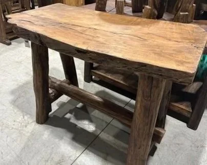 A rustic wooden table with a natural, uneven surface surrounded by wooden chairs in a furniture store.