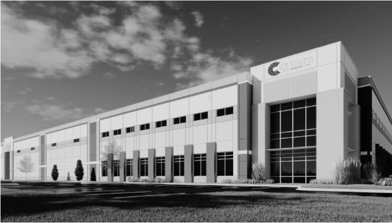 Modern industrial building with large windows and minimal landscaping under a partly cloudy sky.