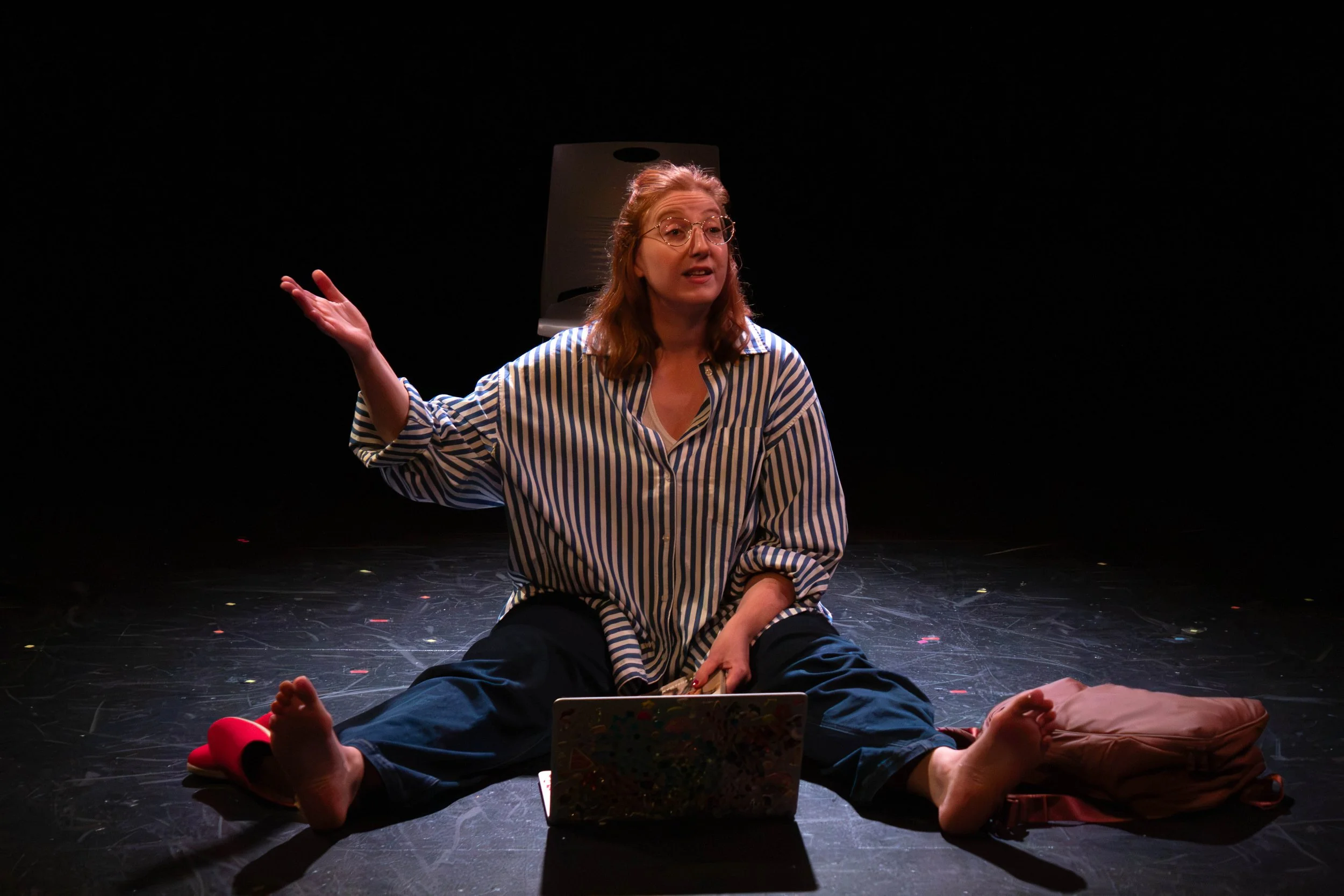 Performer Vanessa Meyer seated on stage floor with a laptop during a live performance.