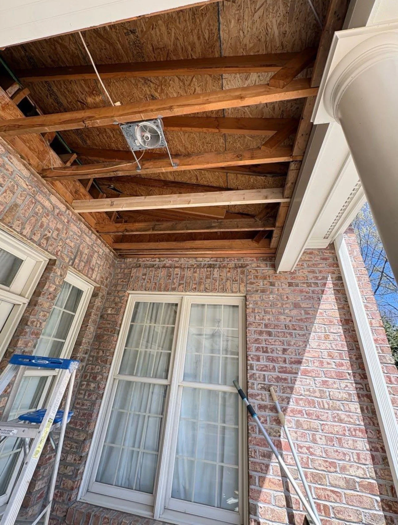 Porch ceiling opened to expose the wood framing during repair work.