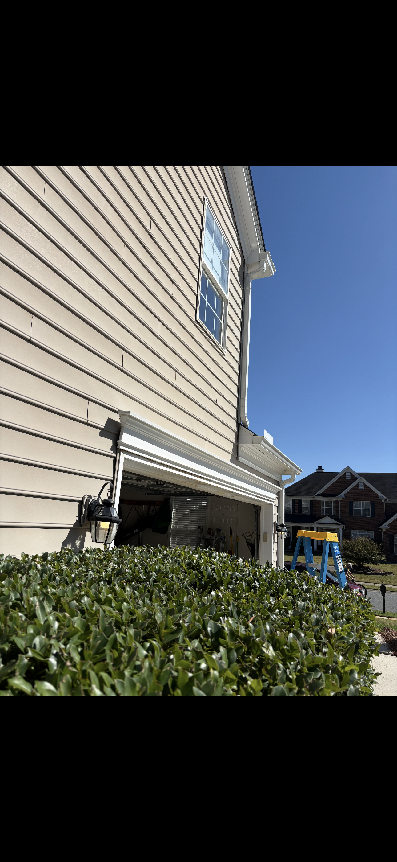 Exterior trim removed above the garage-door opening during repairs to address water intrusion behind the original trim and deterioration of the header structure.