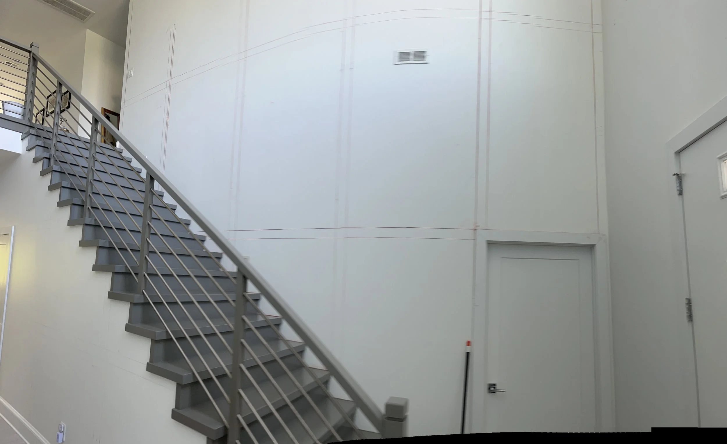 Stairwell with white walls, panel trim, and cable railing.