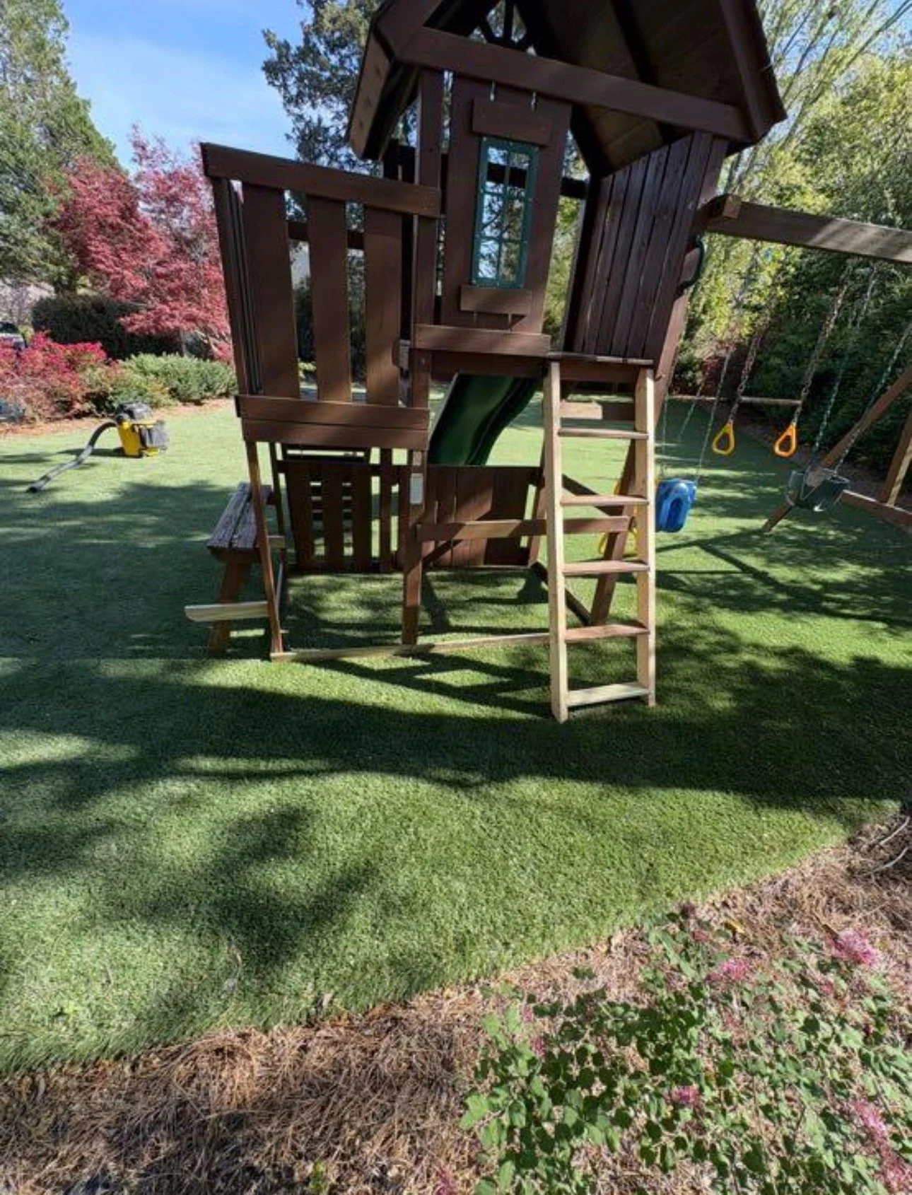 Backyard wooden playset with ladder and raised platform.