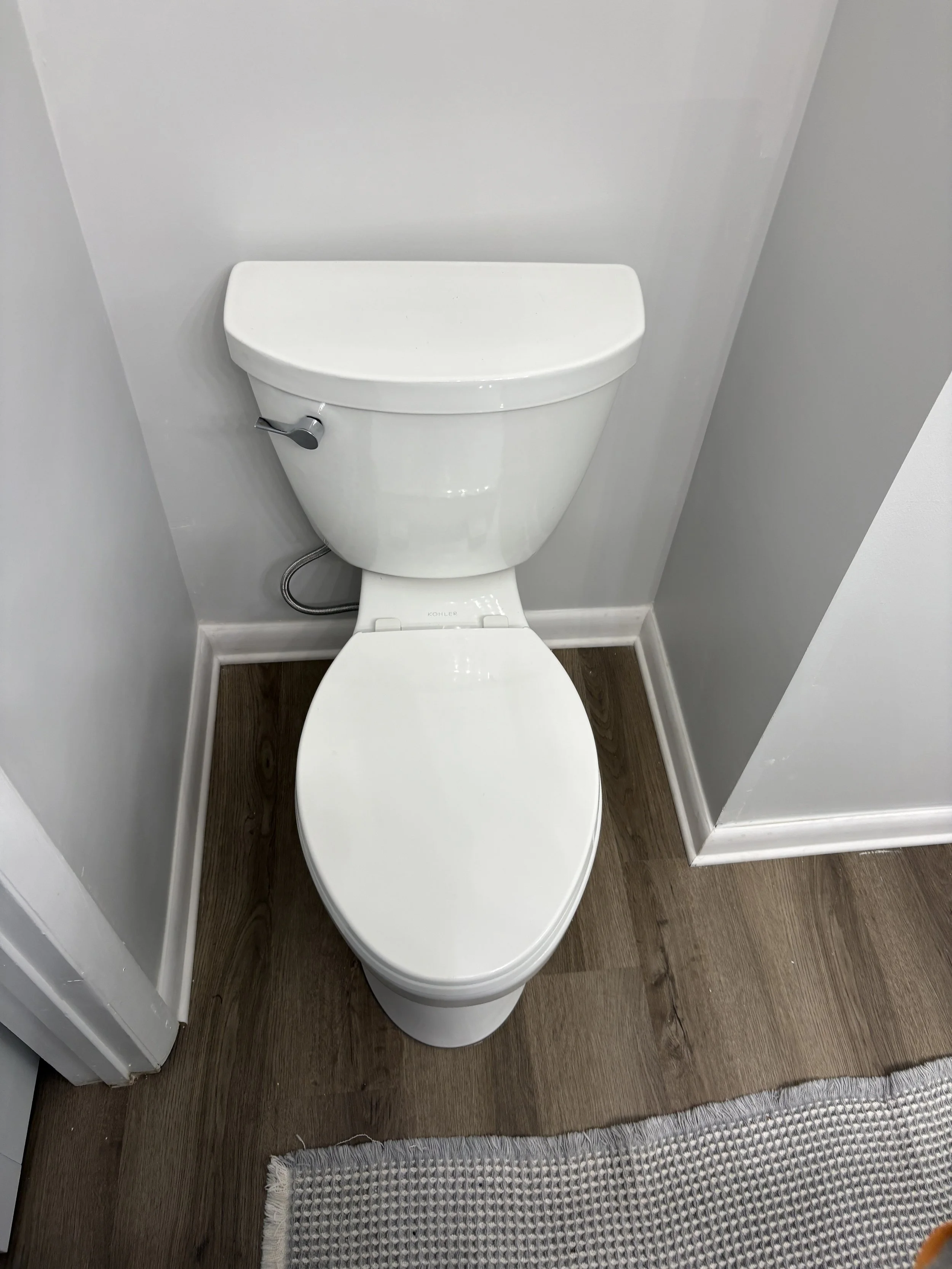 Toilet and wood-look flooring in a small bathroom.