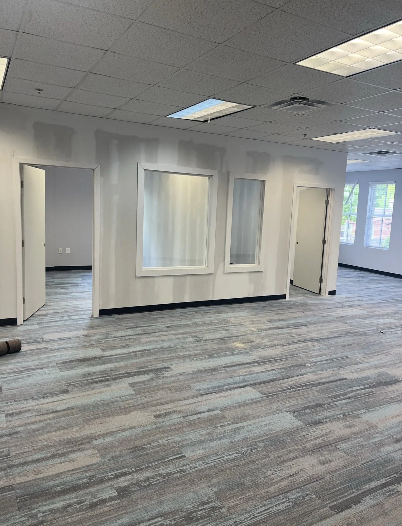 Drywall partition walls with interior window and doorway openings in a commercial space with a suspended ceiling.