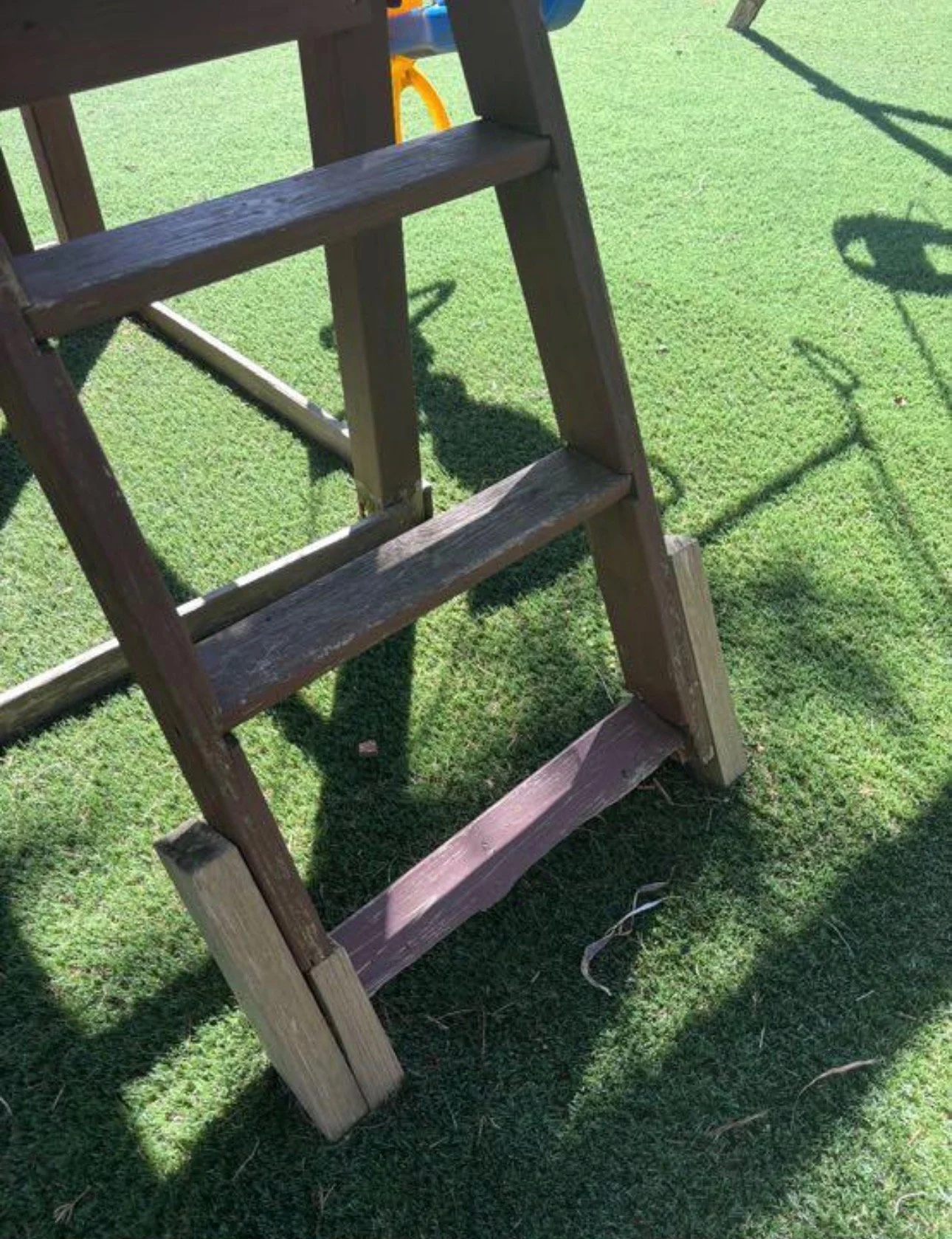 Close view of the wooden ladder and support rails on a backyard playset.