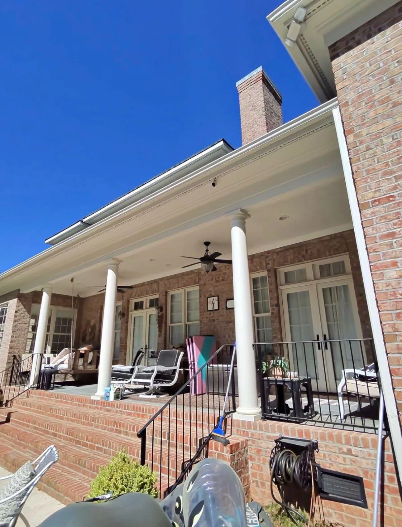 Covered porch with white ceiling, columns, and outdoor seating.