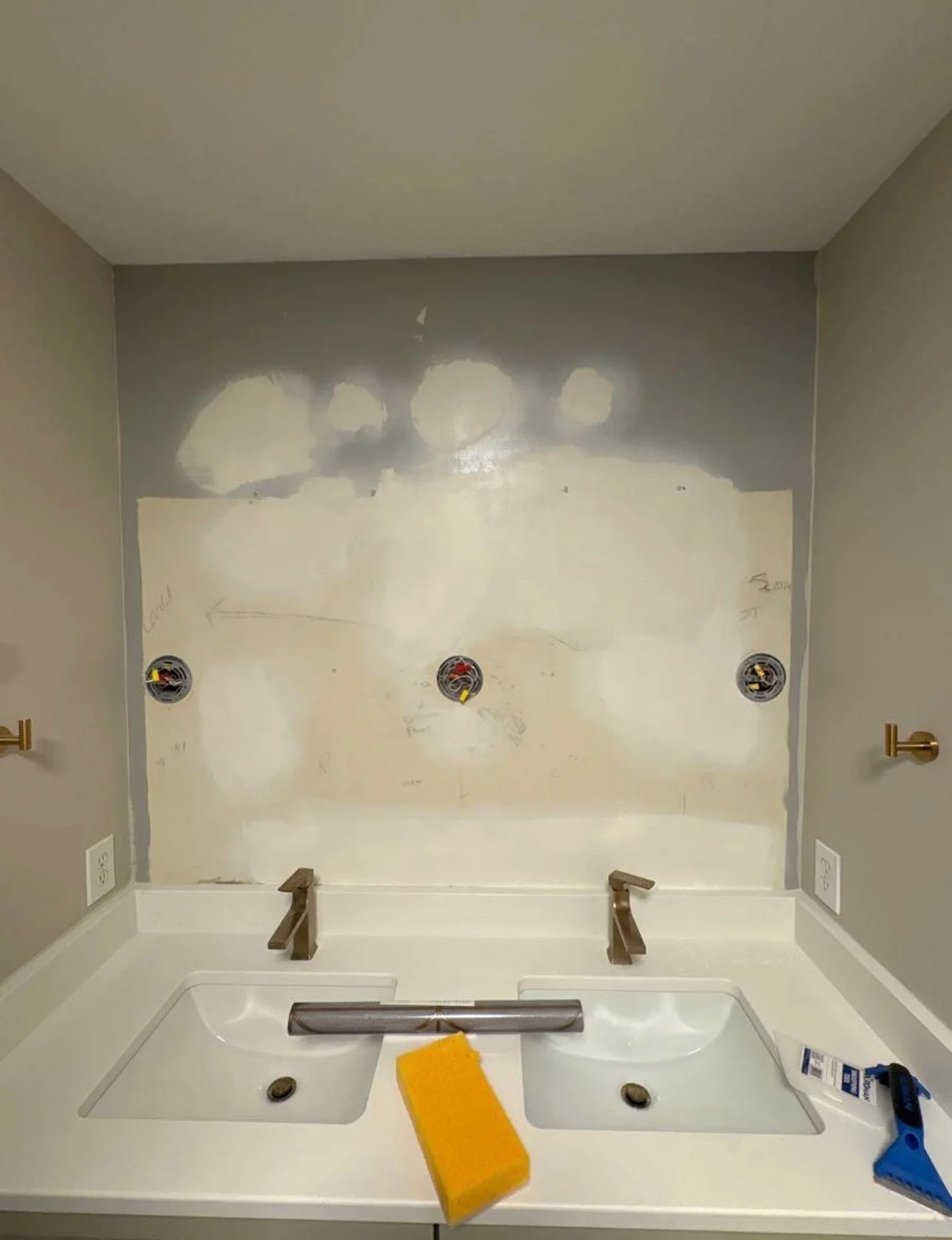 Bathroom wall patching above the vanity before the mirrors were installed.