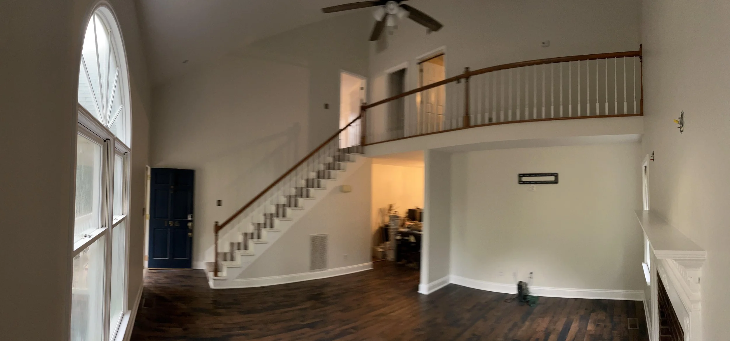 Interior painting project in a two-story living area with staircase and upper railing.