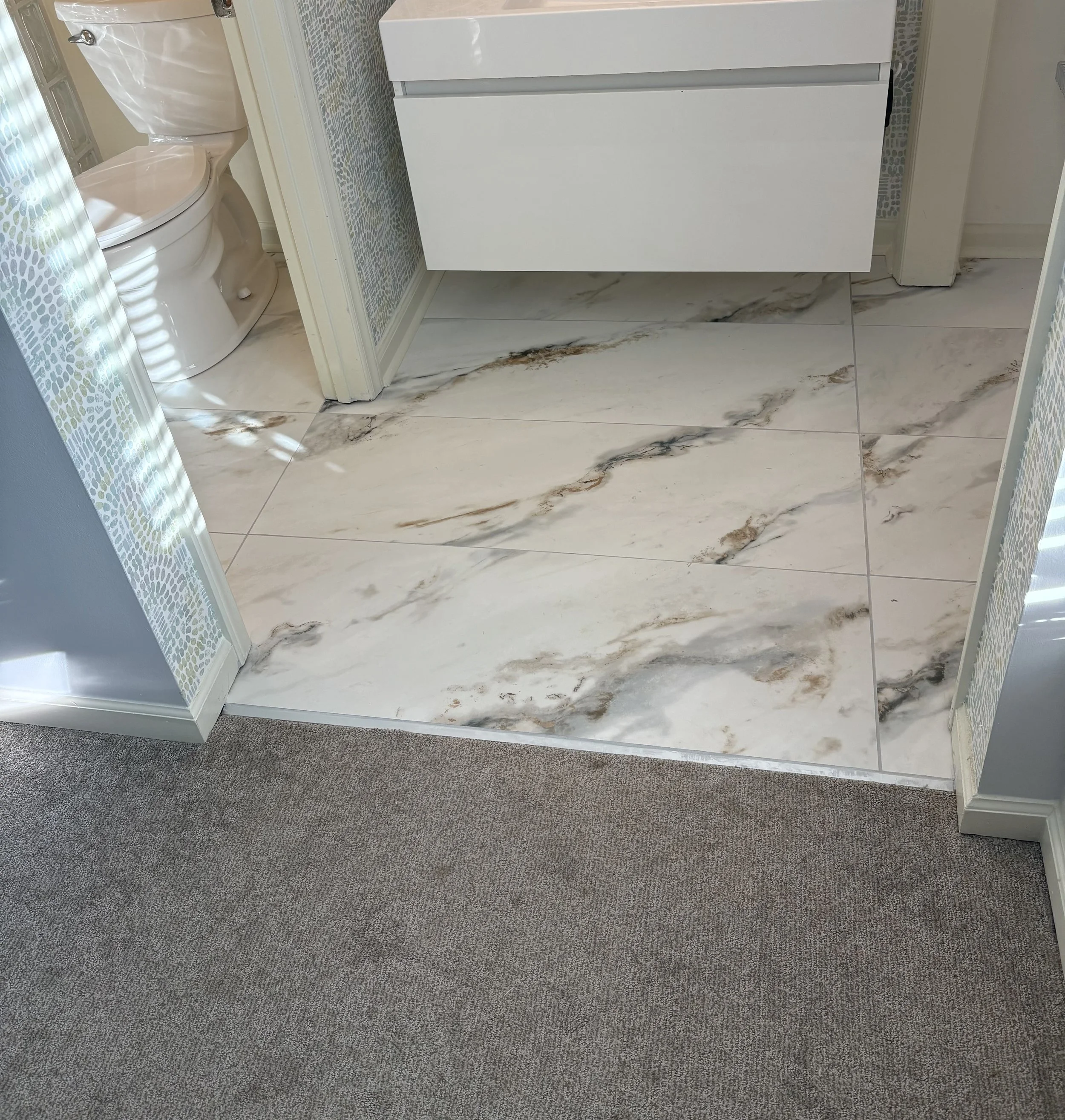 Bathroom floor with marble-look tile around the vanity and doorway.