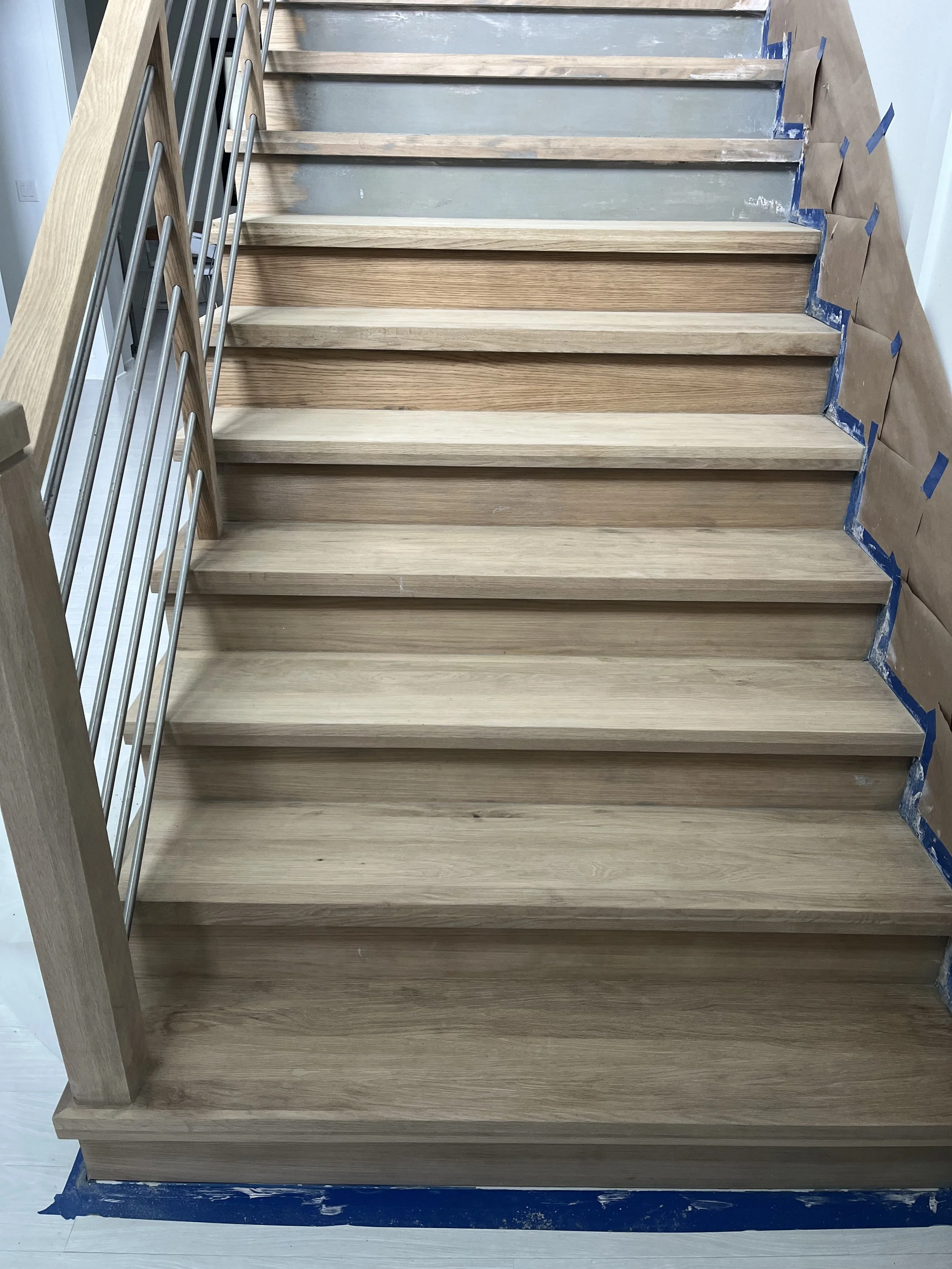 Close view of interior stair treads and white risers beside the railing.