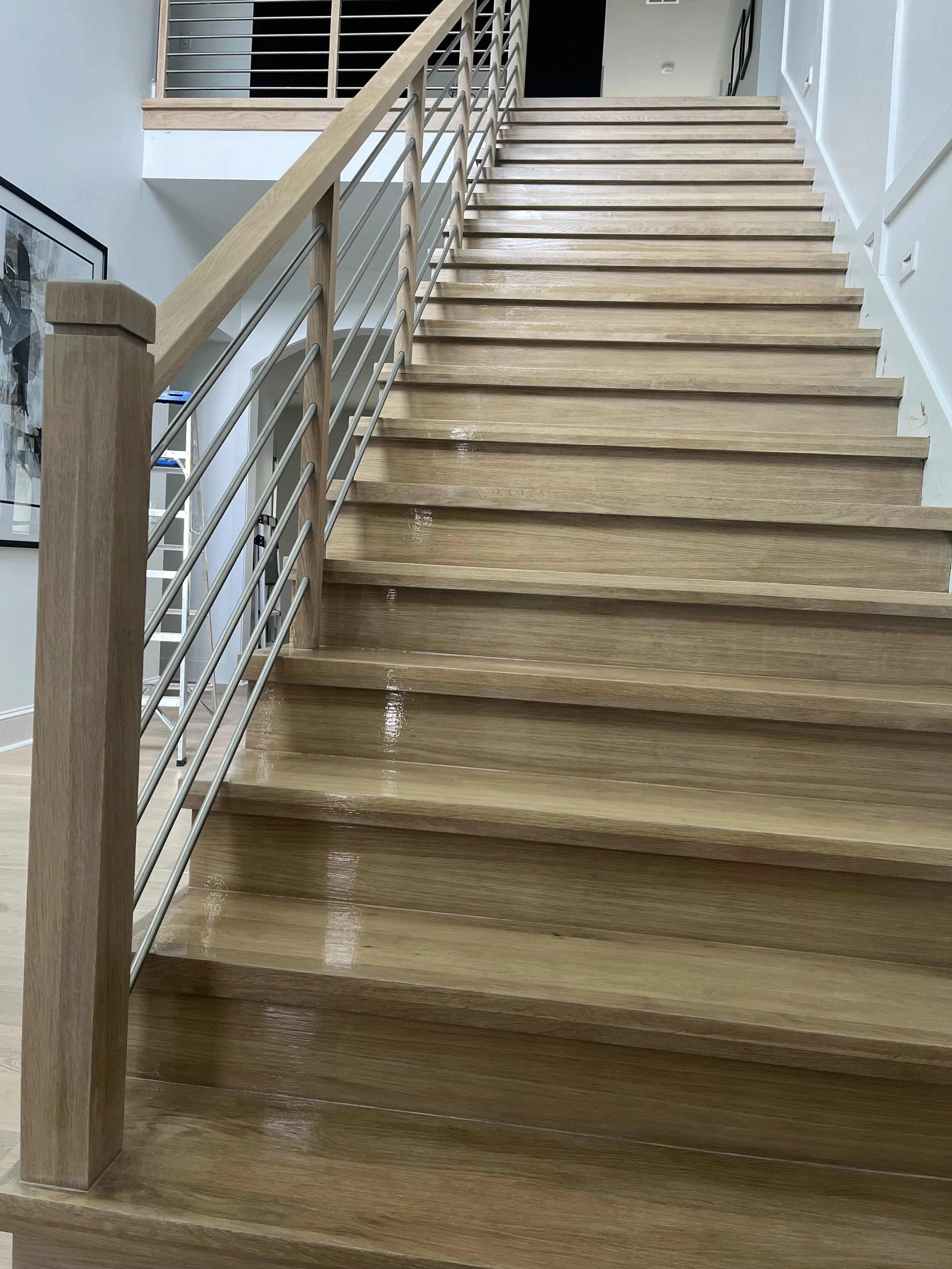 Interior staircase with wood treads, white risers, and decorative railing.