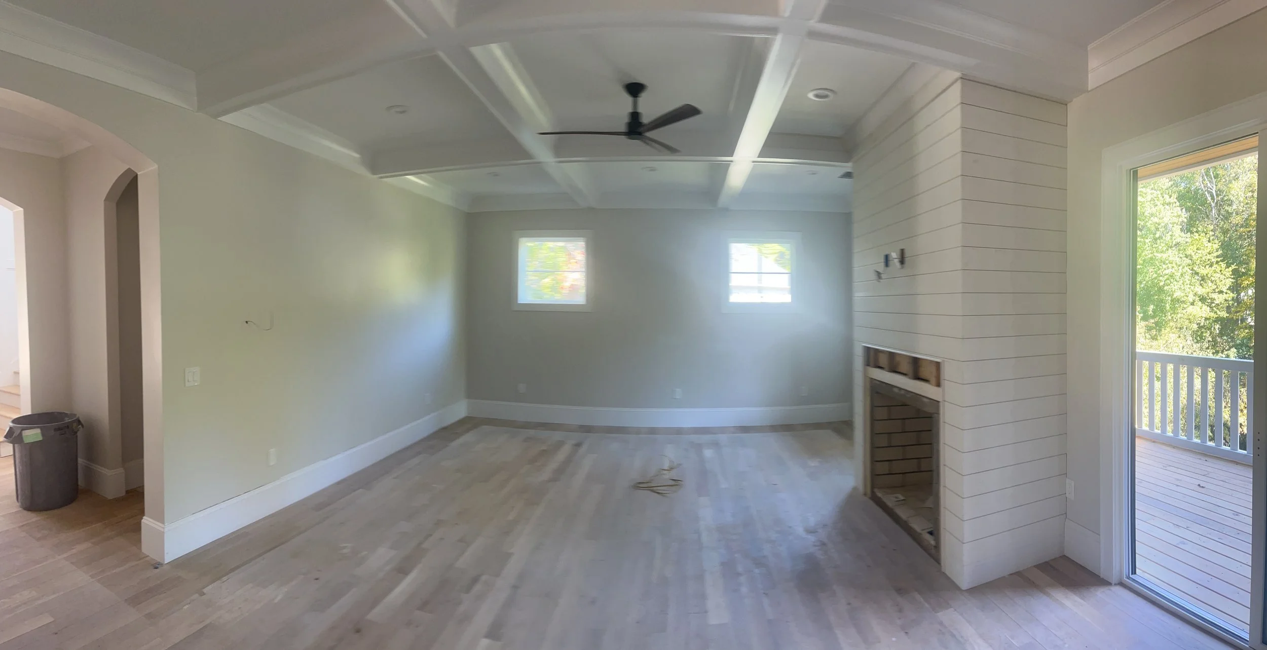 Interior painting in a room with white walls, ceiling beams, and a ceiling fan.