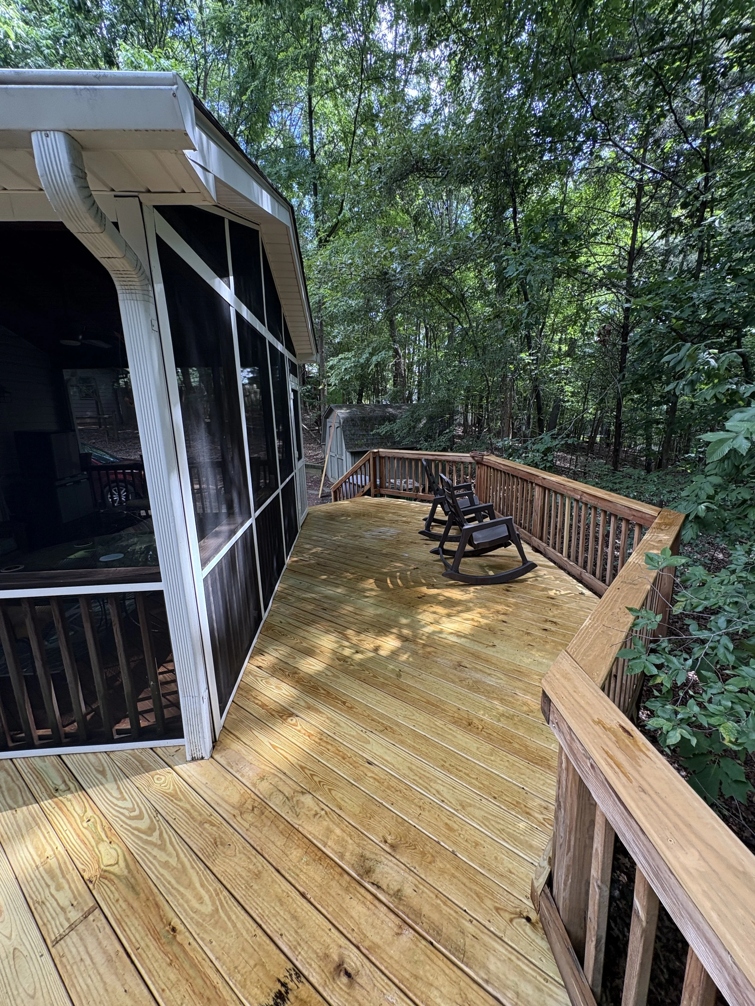 Wood deck adjoining a screened porch, showing the deck boards and perimeter railing.