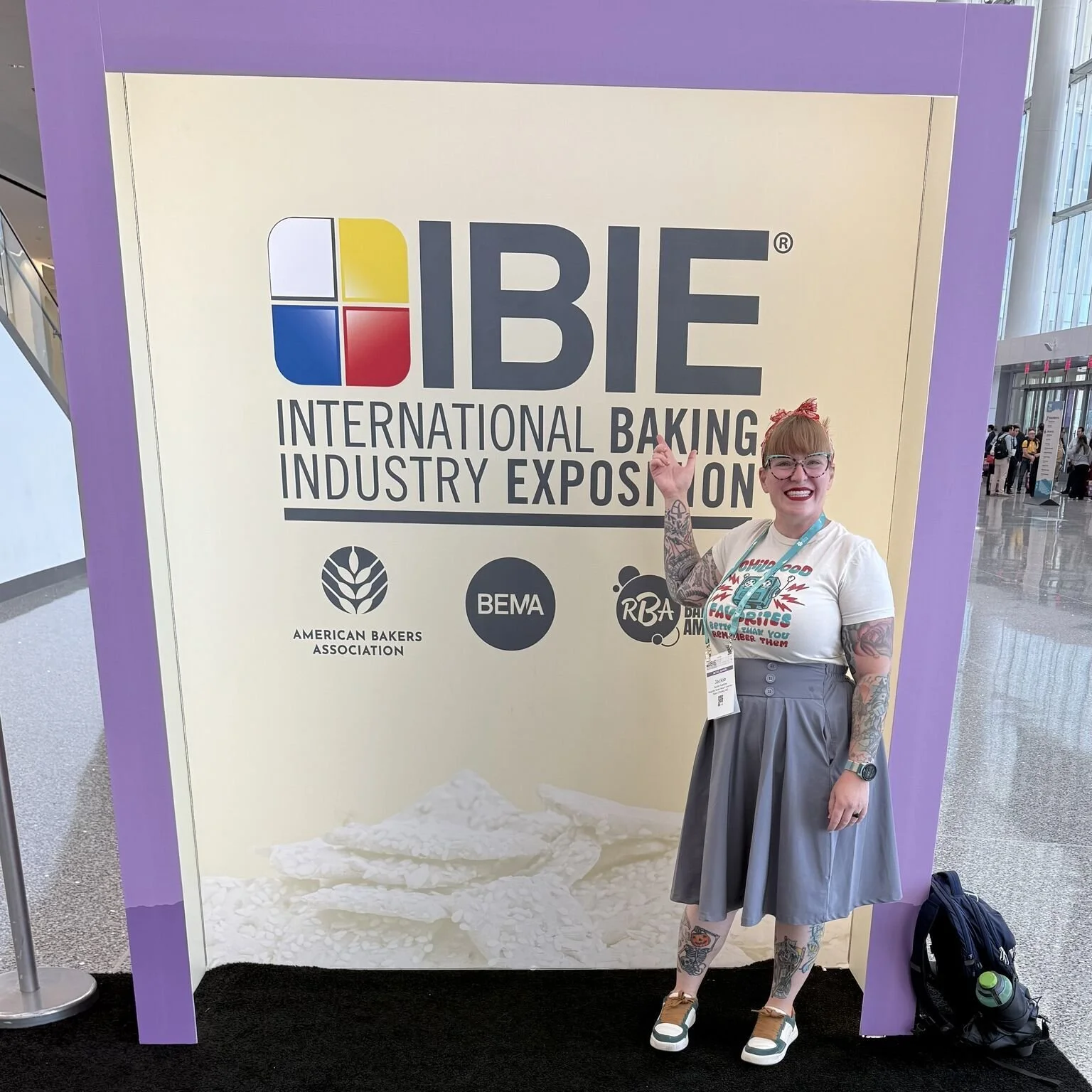 Jackie Huebbe, owner of SugarBot Sweet Shop & Creamery, poses with sign at the International Baking Industry Exposition