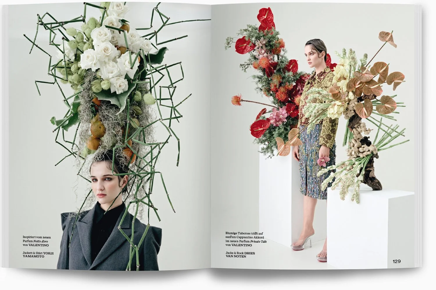 Modische Modelle in Designer-Outfits, umgeben von großen, kreativen Blumenskulpturen, auf einer weißen Galeriewand präsentiert.