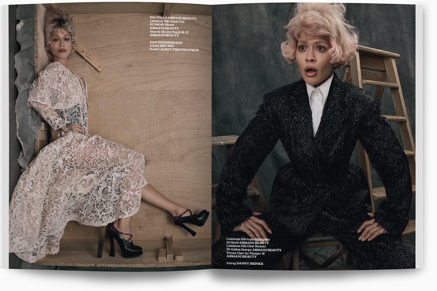 Zwei Frauen in Modefotos, eine liegt auf dem Boden in einem weißen Spitzenkleid und hohen schwarzen Schuhen, die andere sitzt vor einer Leiter mit einem schwarzen, glitzrigen Anzug. Beide haben pinke, lockige Haare.