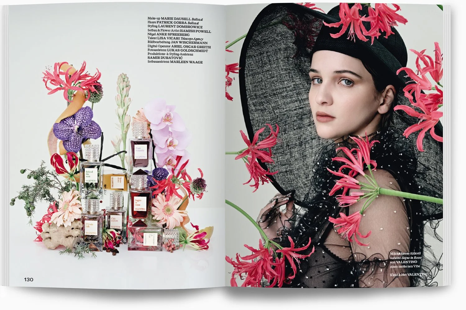 Eine Modelfrau trägt ein schwarzes, transparentes Kleid mit Perlen und trägt einen großen schwarzen Hut, der von pinken Blumen umgeben ist.