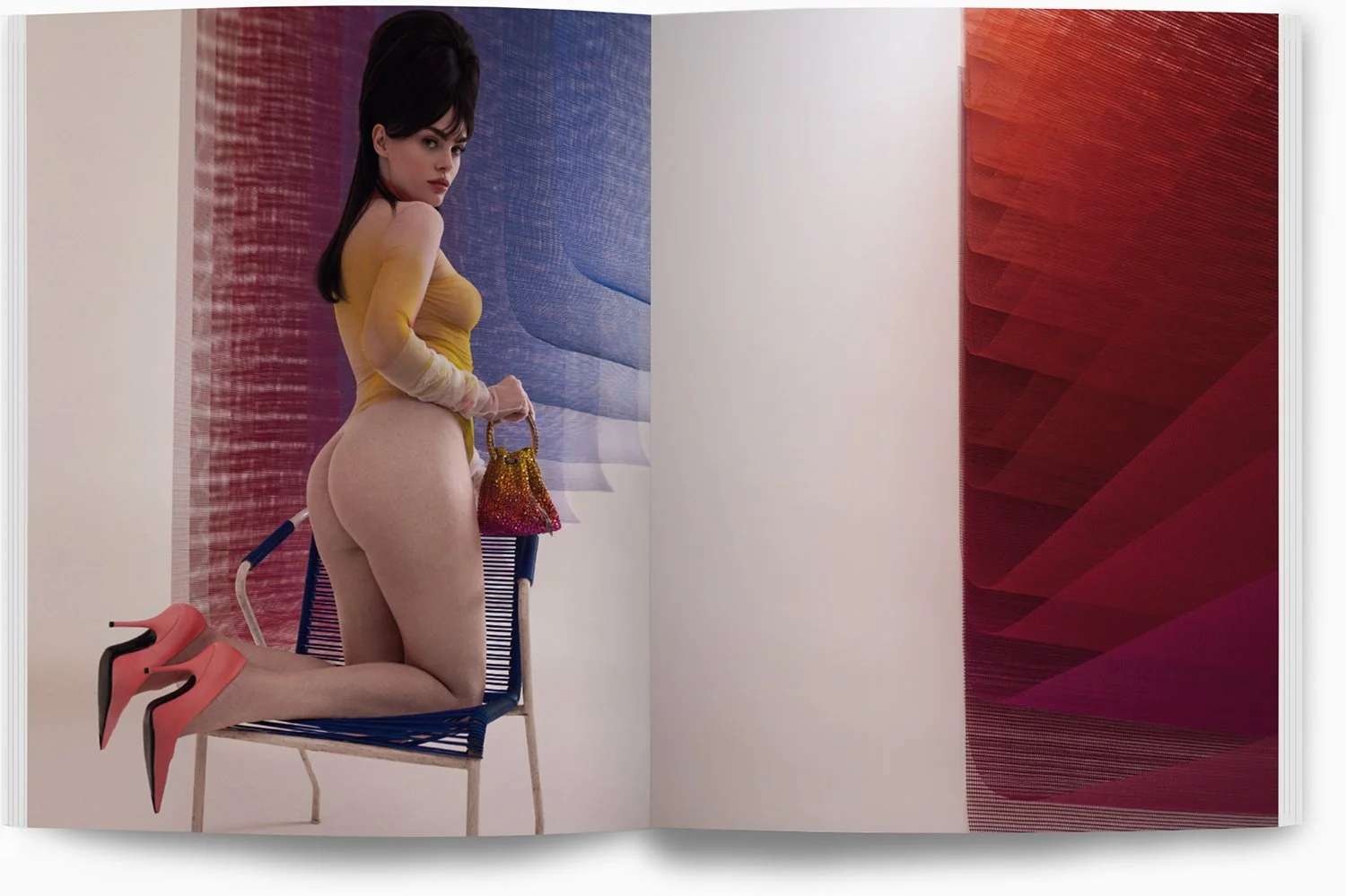 Frau in gelbem Oberteil, nackend, auf einem Stuhl kniend mit roten High Heels, hält eine bunte Handtasche, steht vor einer farbigen Wandinstallation.