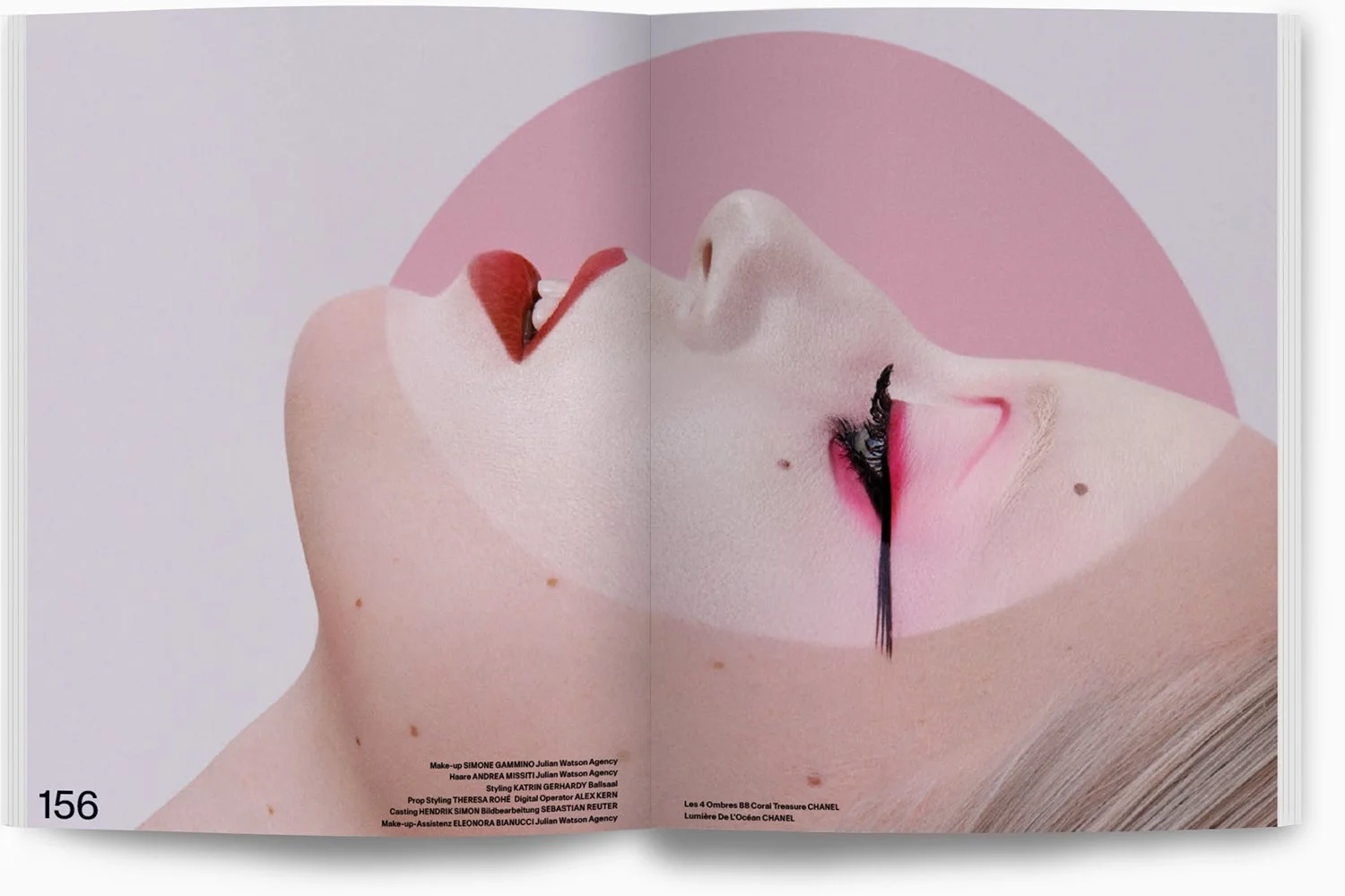 Nahaufnahme eines Gesichts einer Frau mit Make-up, pinken Lippen, roten und schwarzen Lidschatten, und mehreren Muttermalen auf der Haut, mit einer pinken halbkreisförmigen Hintergrunderweiterung.