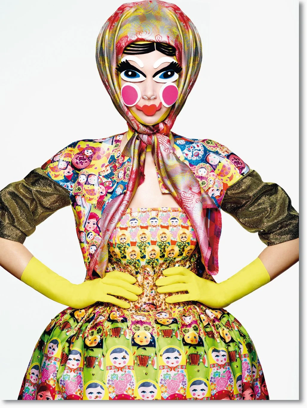 Kunstvolle Puppe im bunten, traditionellen russischen Kleid mit buntem Kopftuch, mit übertriebenem Make-up und auffälligem Gesicht. Sie trägt gelbe Handschuhe.