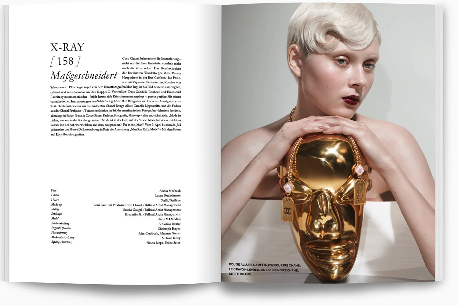 Eine Frau mit blonder Kurzhaarfrisur, rotem Lippenstift und Schmuck hält eine goldene, maskenartige Tasche mit einer Chanel-Tag. Die Seite enthält einen Text über eine Mode- oder Kunstpräsentation mit technischen Details im unteren Bereich.