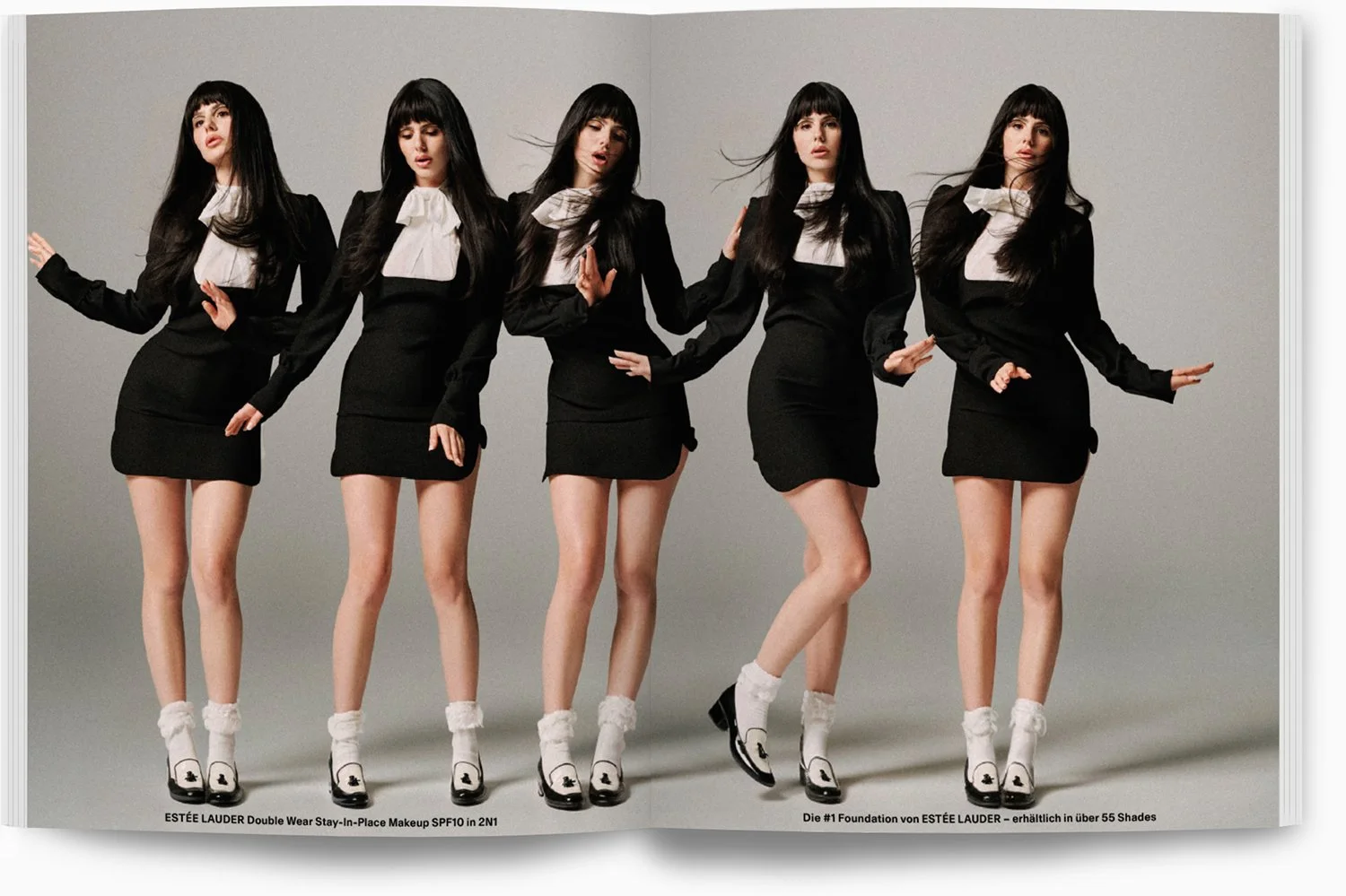 Fünf Frauen in schwarz-weißer Kleidung posieren vor grauem Hintergrund, tragen weiße Socken und schwarze Schuhe.