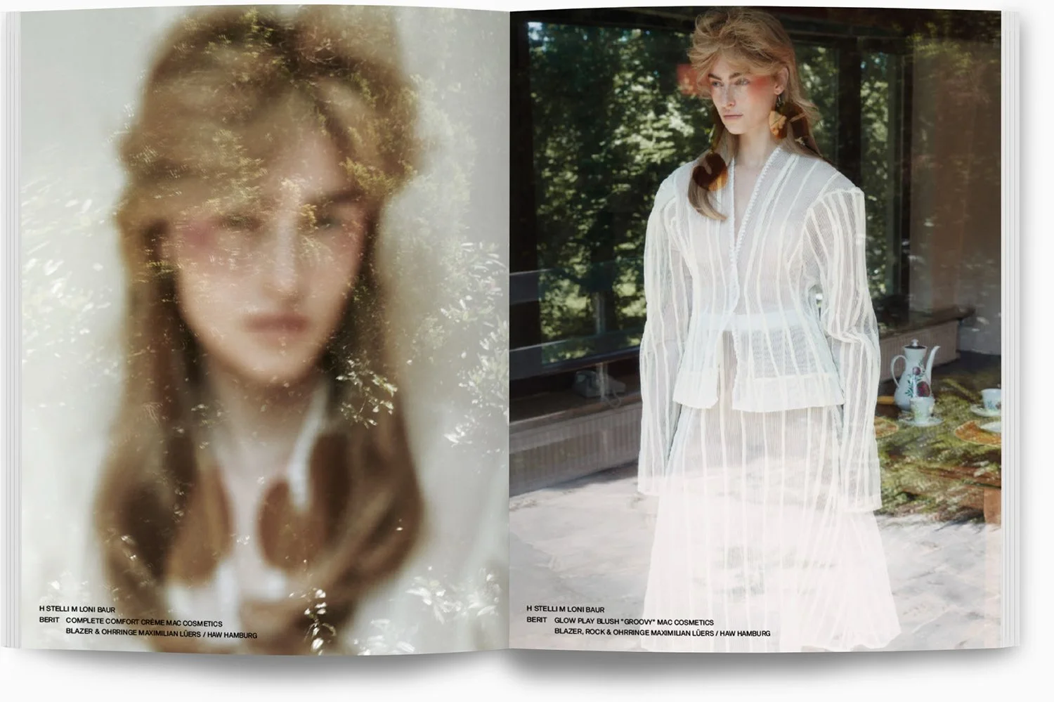 Zwei Frauen in einem Magazin. Die linke Frau ist unscharf und hinter einer reflektierenden Oberfläche, die rechte Frau steht vor einem Fenster im Freien mit Grün im Hintergrund. Sie trägt ein weißes, halbtransparentes Kleid mit vertikalen Streifen un