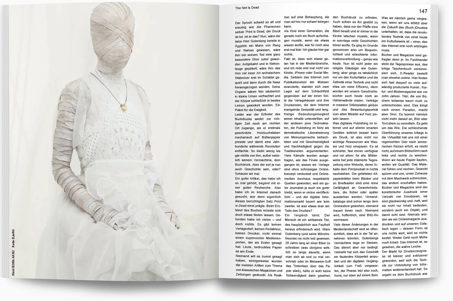 Ein gezeichneter Kleiderständer oder Puppen, eingewickelt in Watte, trägt eine weiße, perforierte Kleidung und eine Kette mit einem Herzanhänger. Im Hintergrund weiße Wände.