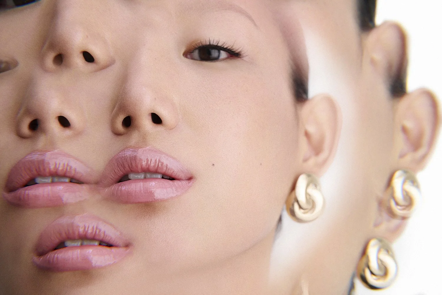 Close-up of person with layered face and multiple earrings, showcasing makeup and jewelry.