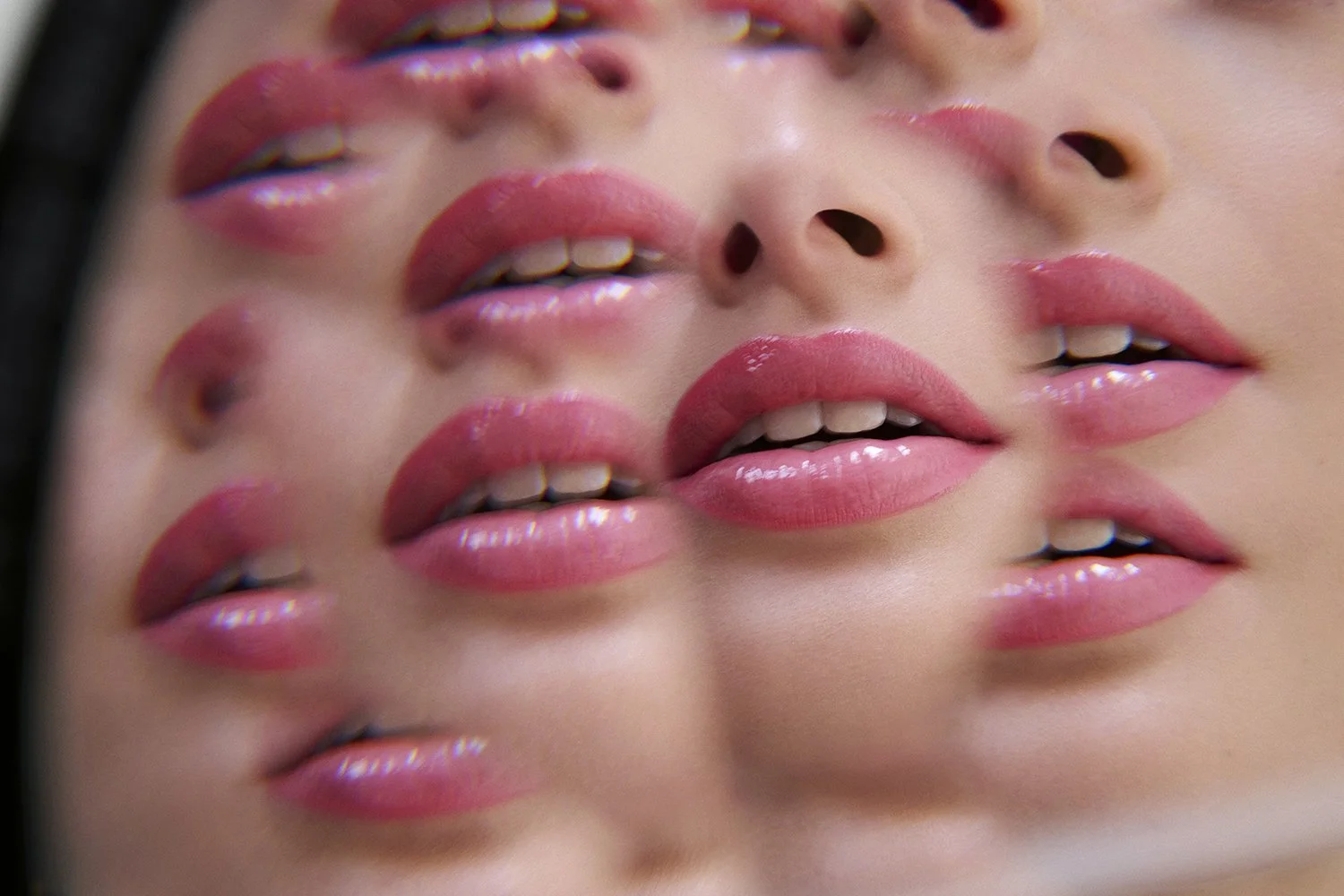 Multiple repetitions of a woman's face showcasing glossy pink lips and nose, create a layered, artistic visual effect.