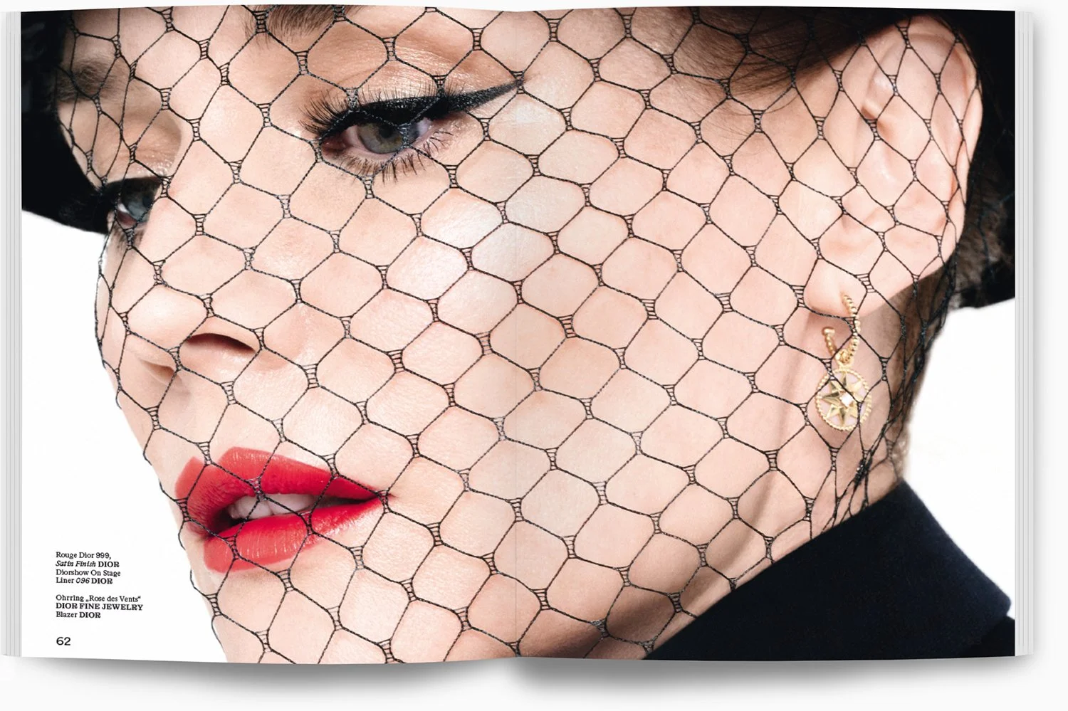 Nahaufnahme eines Gesichts mit schwarzen Netzstoff, rotem Lippenstift und einer goldenen Ohrring. Der Netzstoff bedeckt das Gesicht teilweise.