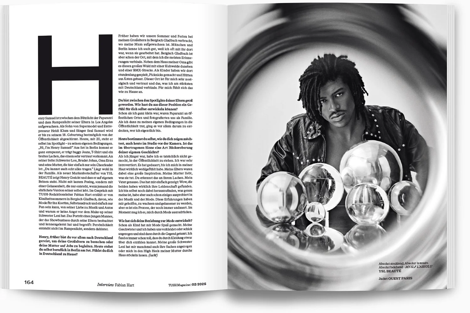 Schwarze und weiße Fotografie eines jungen Mannes mit dreadlocks, der eine Lederjacke trägt, vor einer reflektierenden Oberfläche mit mehreren Glaskugeln. Die Gegenstände stehen in einem Kreis und das Bild ist verzerrt durch eine spiralförmige Verzer