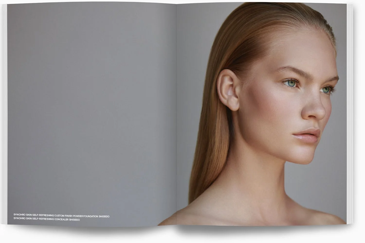 Nahaufnahme eines jungen Frauengesichts mit glatter Haut und gepflegtem, langem, hellbraunem Haar, Blick nach rechts, neutraler Ausdruck, vor grauem Hintergrund.