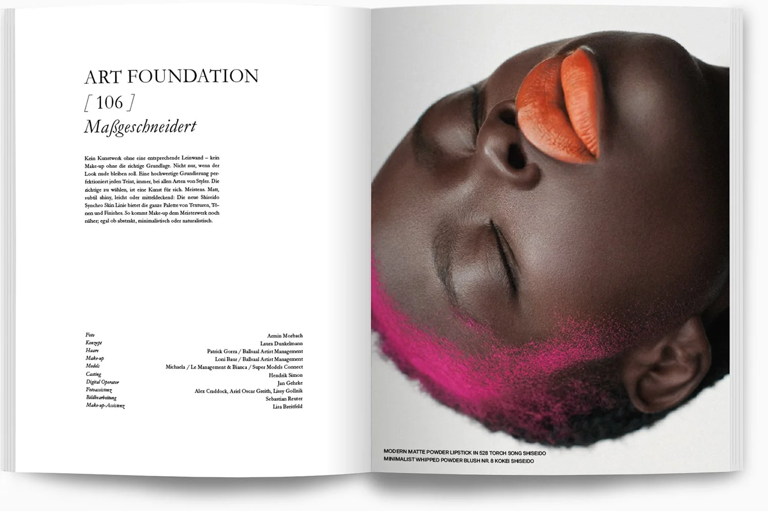 Ein offenes Magazin mit einem Foto einer schwarzen Frau, die mit mattem Lippenstift in einem orangenen Farbton und pinkfarbenem Puder-Make-up geschminkt ist, die Augen geschlossen und den Kopf zur Seite gelegt. Der Text auf der linken Seite beschreib