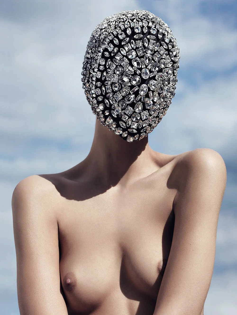 Person mit nacktem Oberkörper trägt eine Maske aus glitzernden Kristallen.